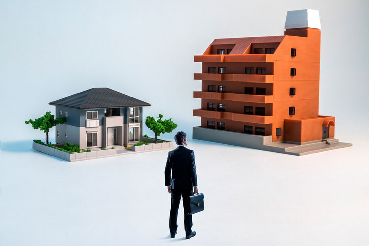 Businessman looking at na house and a apartment building